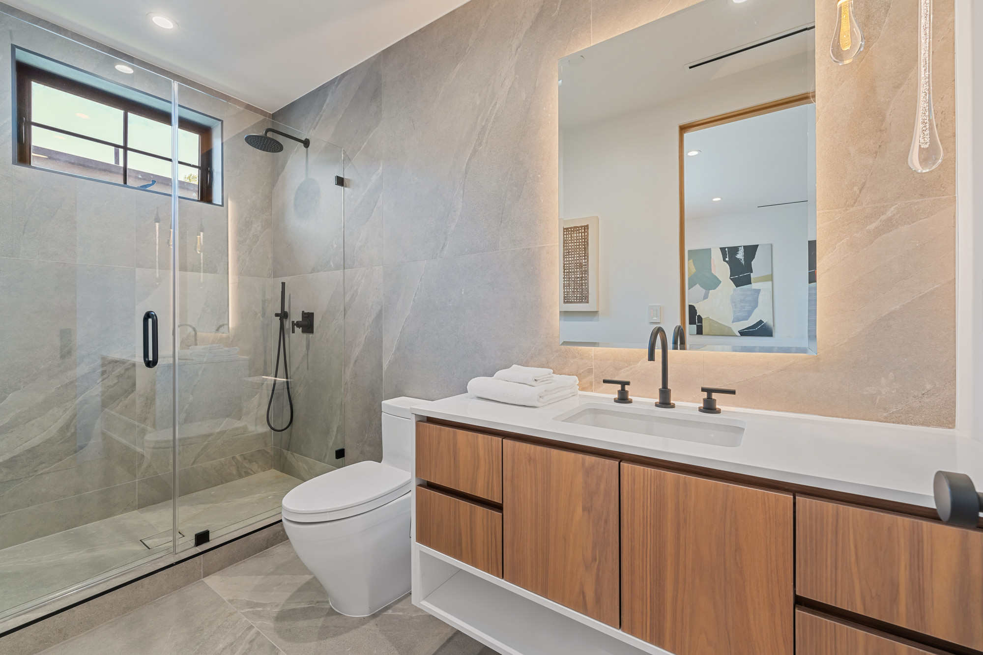 Walnut floating vanity with honed stone top and matte black hardware