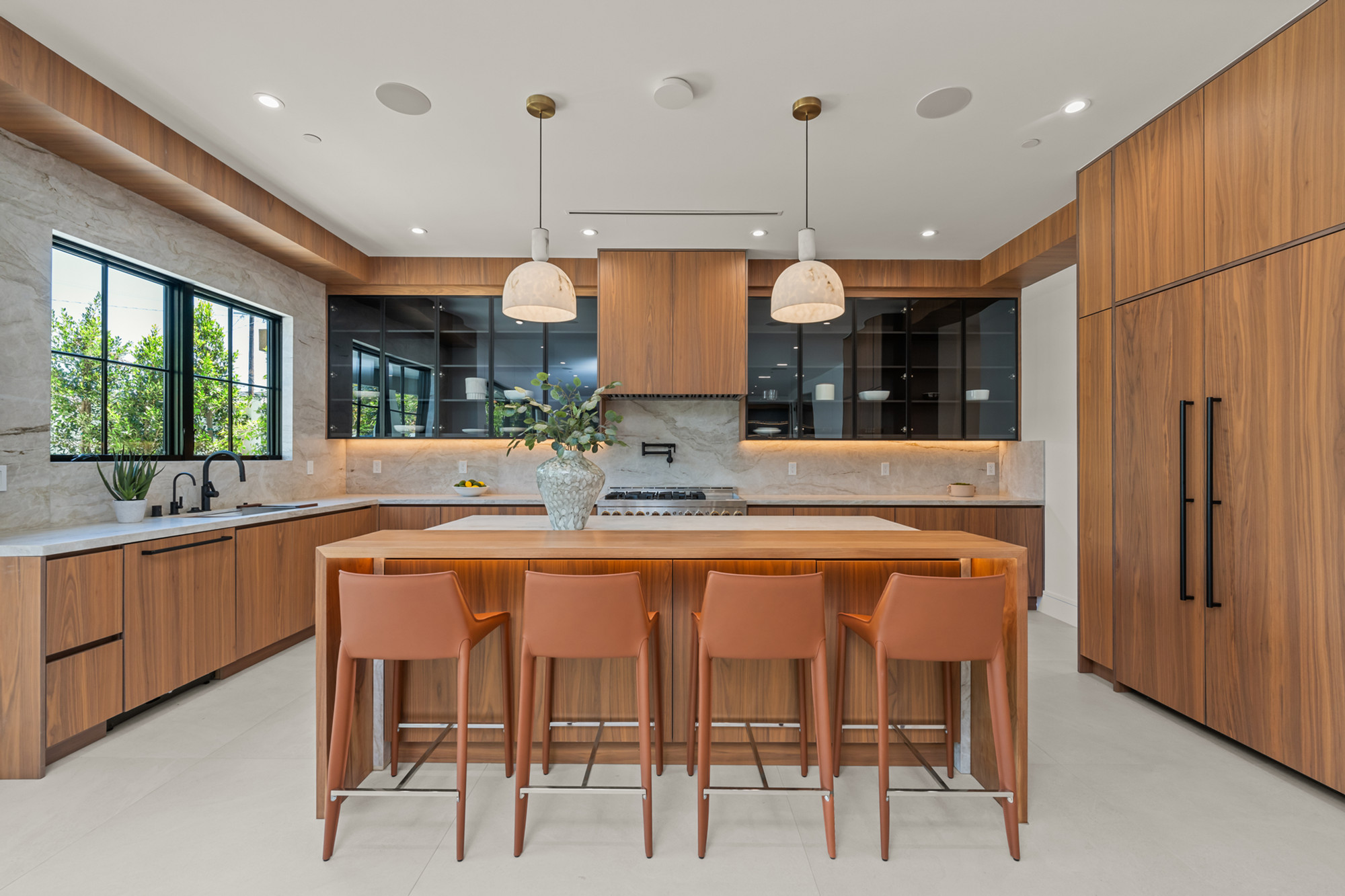Walnut kitchen with honed marble counter and brass pendants